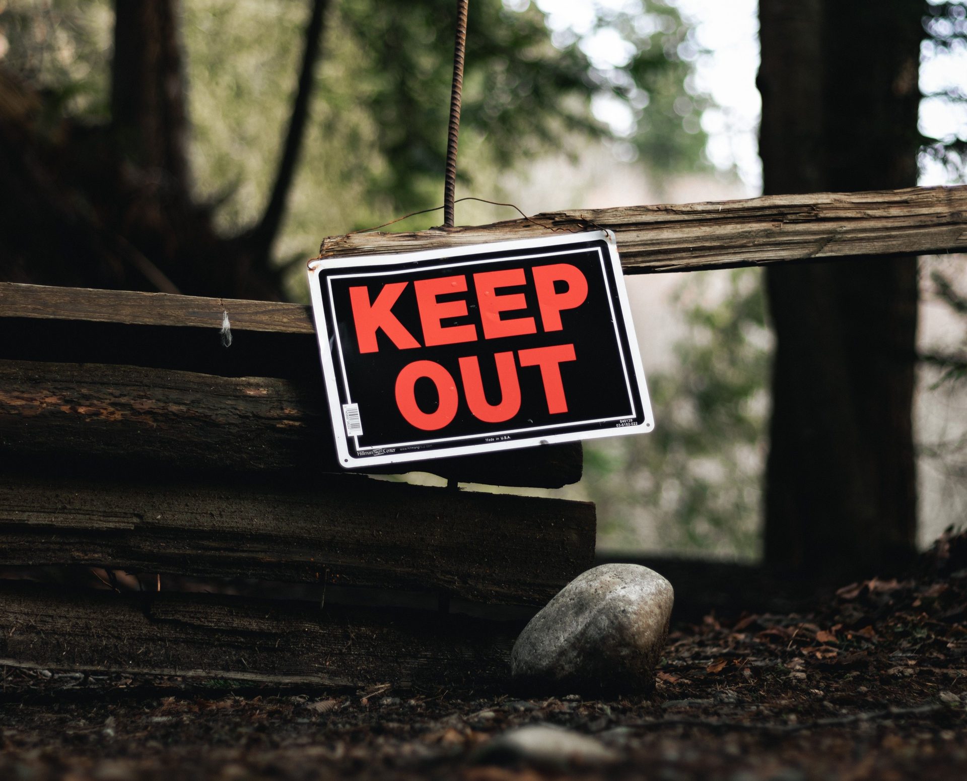 A KEEP OUT sign on a worn wooden fence – old patterns guard what feels safe